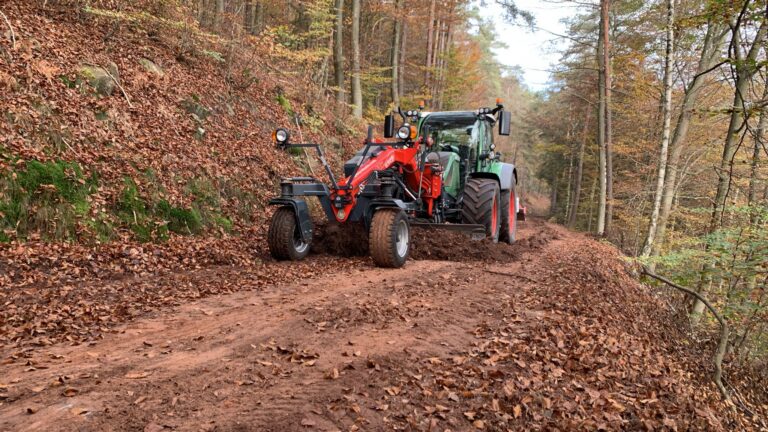 Niveleuse PTH montée à l'avant d'un tracteur Fendt lors du nivellement d'une route forestière